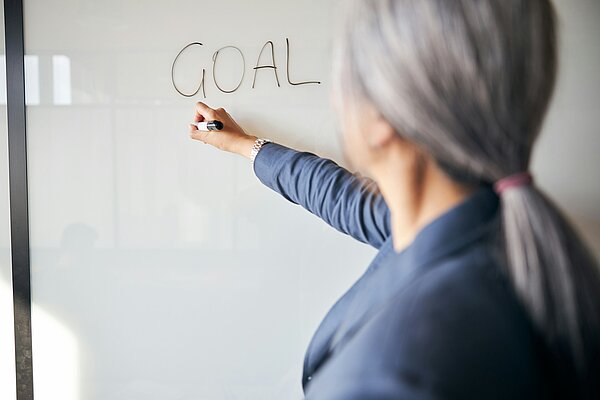 Frau bei der gemeinsamen Zielplanung am Whiteboard – Zielemanagement als Schlüssel für Klarheit, Motivation und bessere Abläufe im Unternehmen