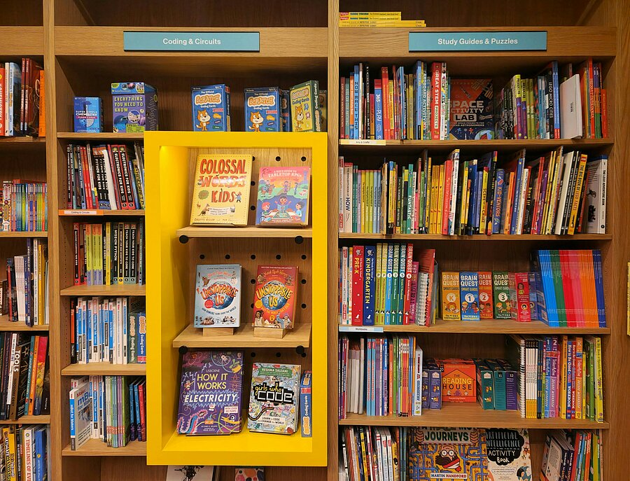 Bunte Kinderbücher in einem Regal einer Buchhandlung, die Wissen, Neugier und Selbstvertrauen fördern.