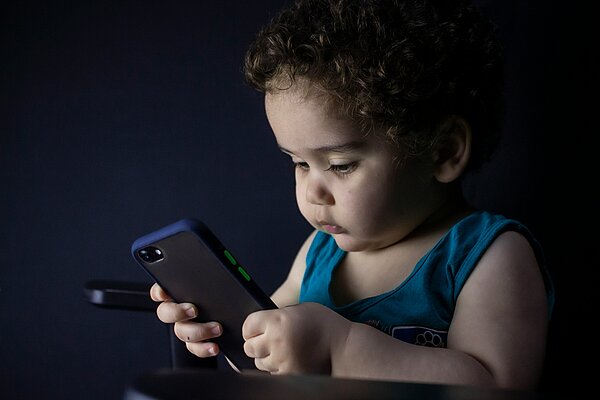Kind schaut konzentriert auf ein Smartphone. Symbolbild für Social Media, Handynutzung und Kinderschutz im digitalen Alltag.