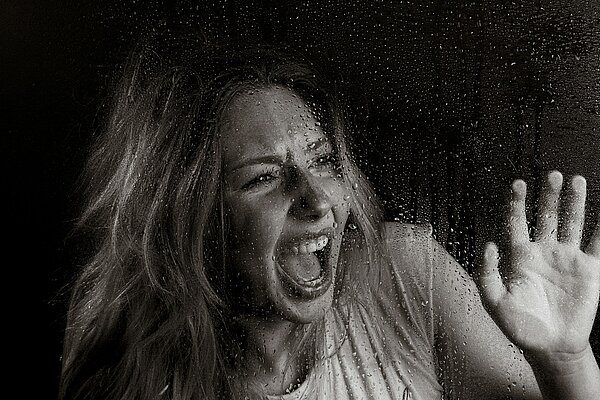 Frau in angespannter Körperhaltung mit unsicherem Blick, Symbolbild für Angstreaktion und Erstarren in Gefahrensituationen – Thema: warum viele nicht schreien können und wie gezieltes Training hilft
