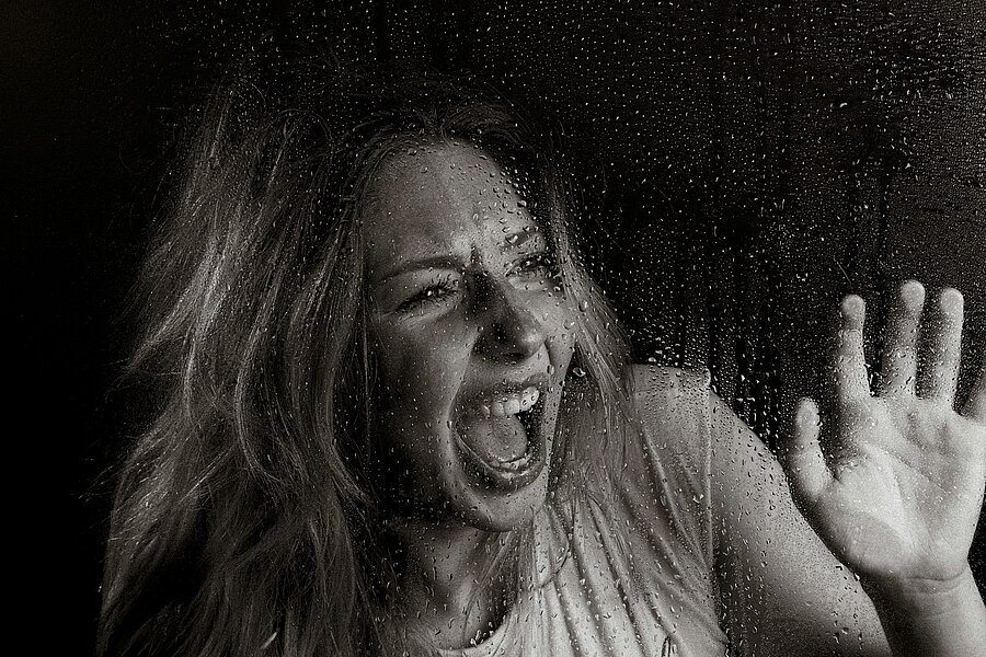 Frau in angespannter Körperhaltung mit unsicherem Blick, Symbolbild für Angstreaktion und Erstarren in Gefahrensituationen – Thema: warum viele nicht schreien können und wie gezieltes Training hilft
