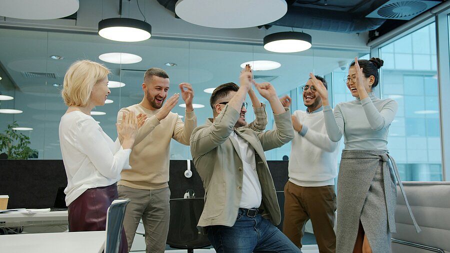 Motiviertes Team freut sich gemeinsam über einen erfolgreichen Abschluss eines Projekts im modernen Büro.