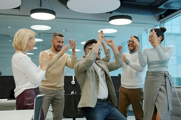 Motiviertes Team freut sich gemeinsam über einen erfolgreichen Abschluss eines Projekts im modernen Büro.