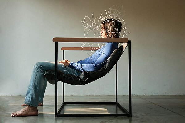 Eine überforderte Person sitzt erschöpft im Stuhl, während chaotische Linien über dem Kopf ihren überladenen Geist symbolisieren – sinnbildlich für Mitarbeitende, die von spontanen Ideen und schnellem Tempo der Führungskraft überrollt werden.